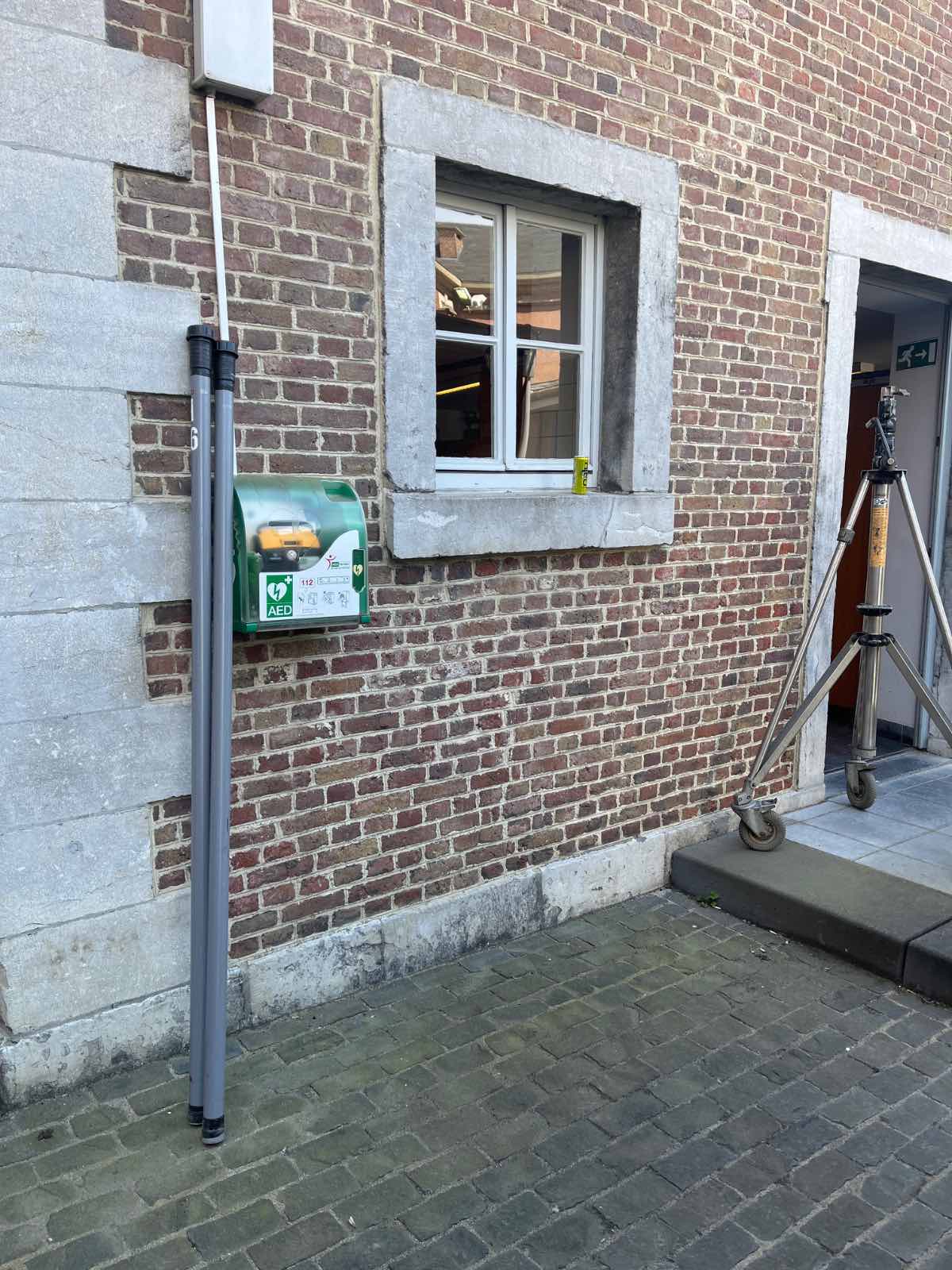 AED Buiten links van de ingangsdeur van de Academiezaal enkel tijdens werkuren en events - poort.