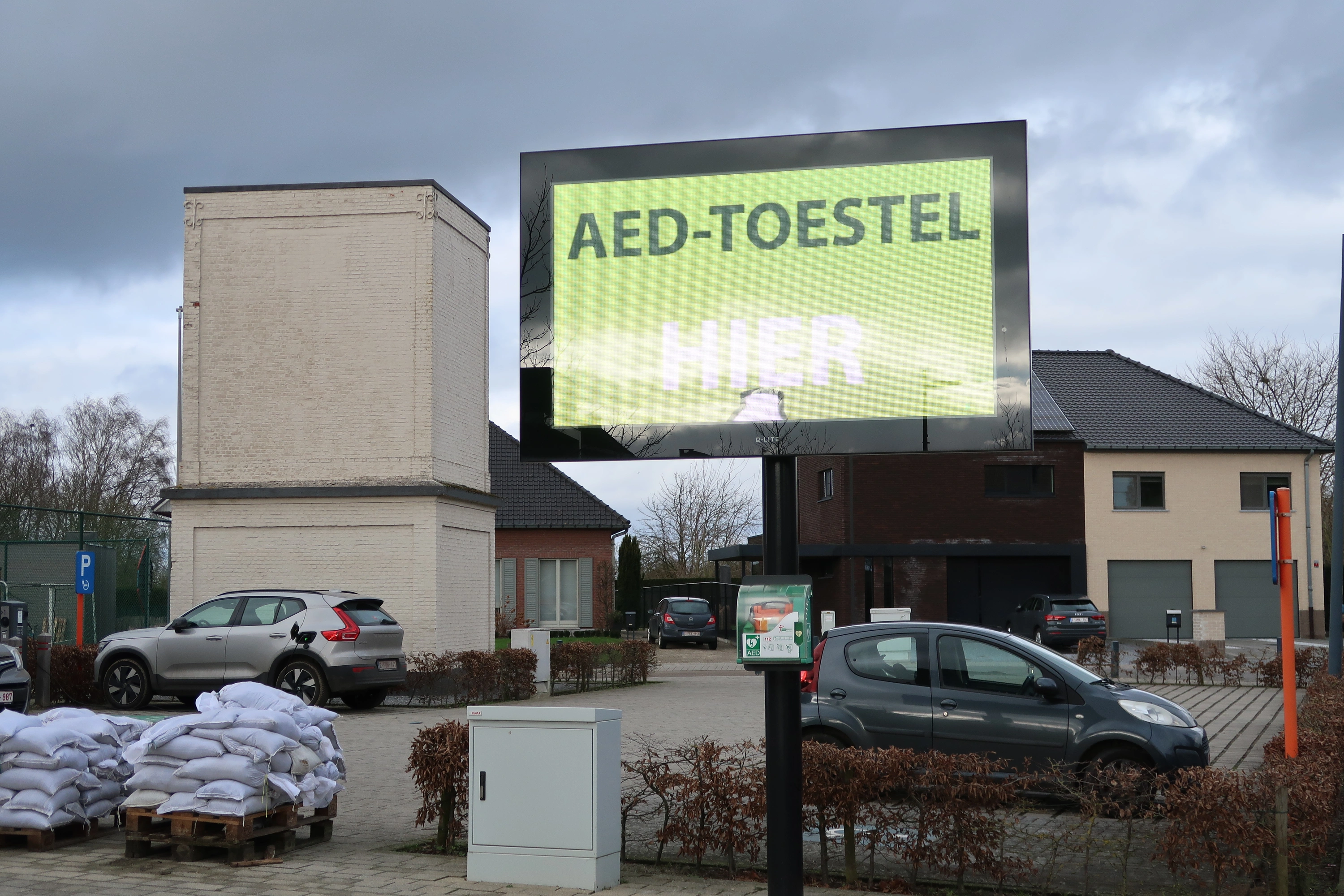 AED Tegen de paal van het infobord op het plein langs de Dorpsstraat voor het vroegere gemeentehuis
