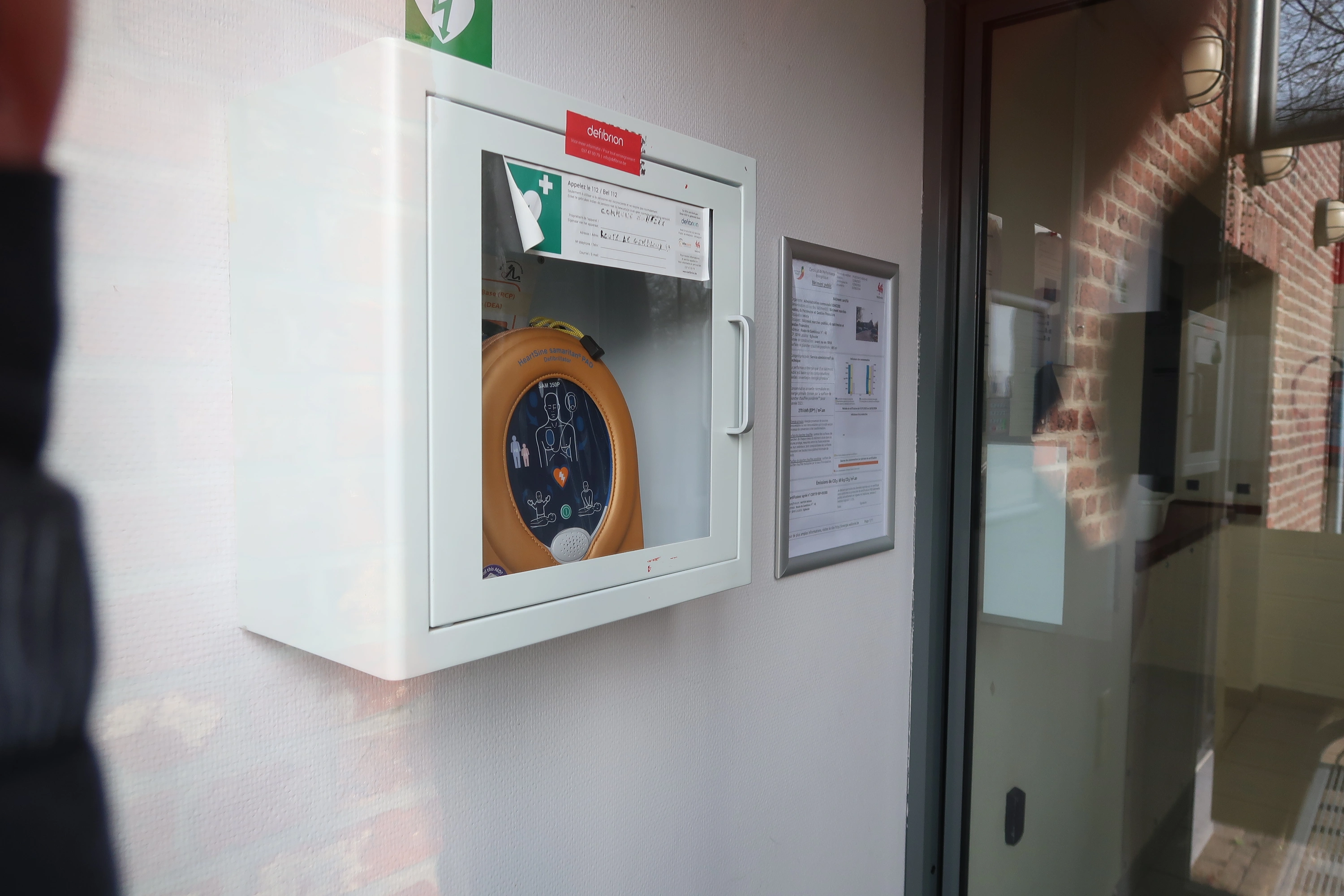 AED In de hall van het oudere gebouw van de gemeentelijke administratie van Eghezée. Links van de ingangsdeur.