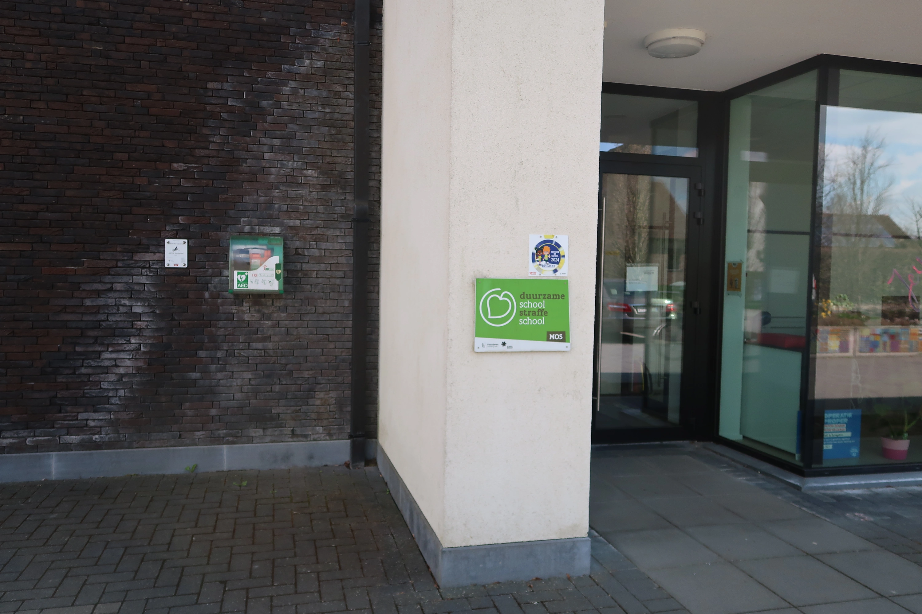 AED Tegen de linkse voorgevel van de school, links van de ingang