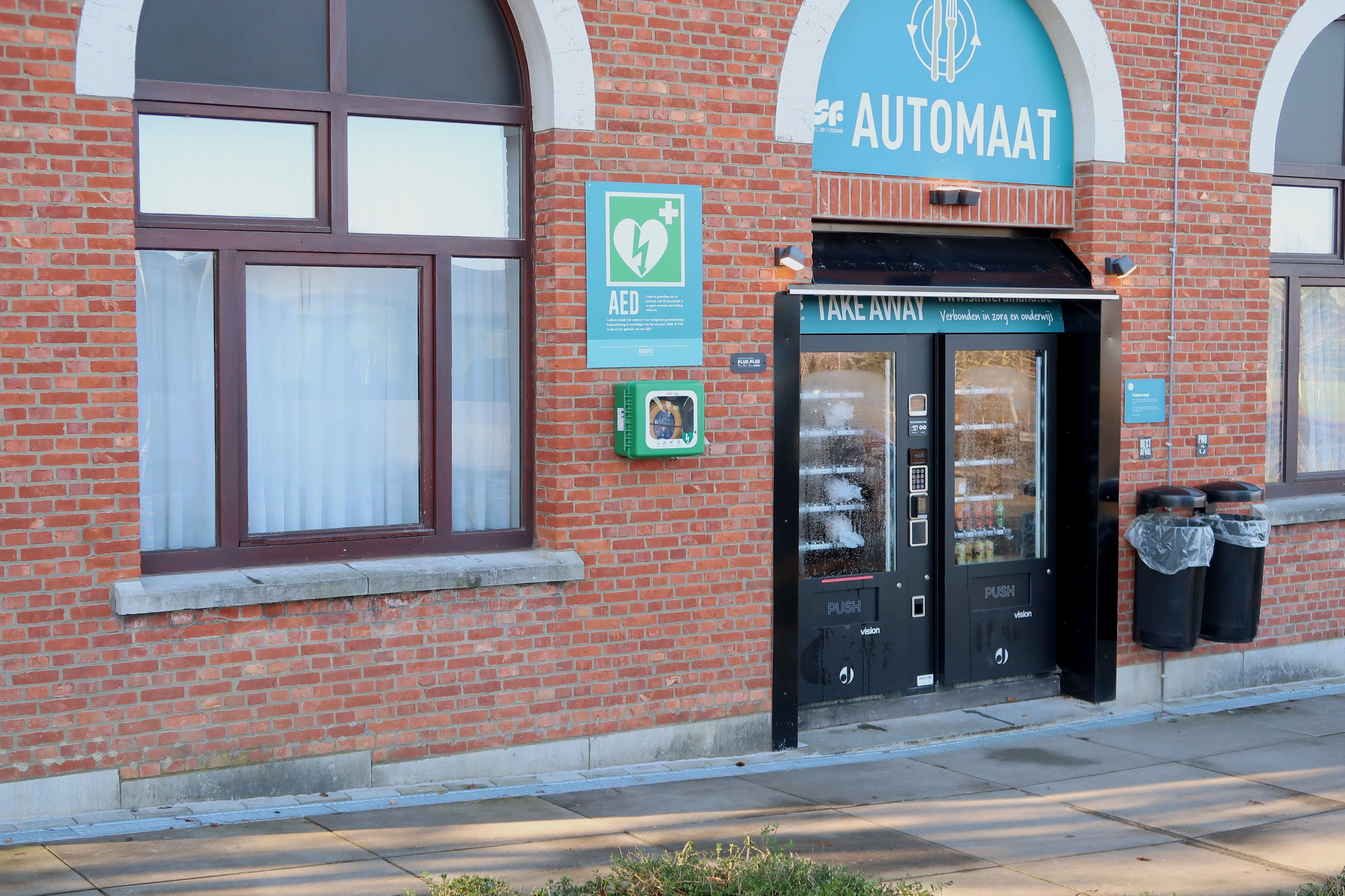 AED Helemaal links tegen de voorgevel van Sint-Ferdinand, naast de automaat