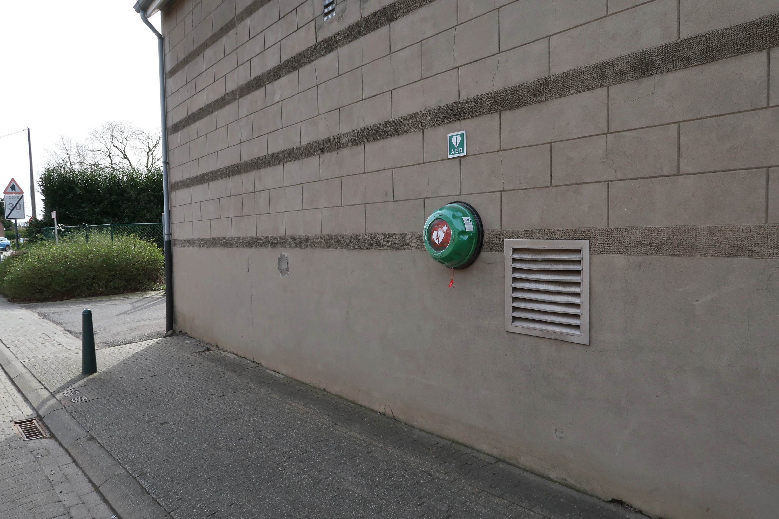 AED Buiten aan de straatkant van Sporthal Winning, links van de poort