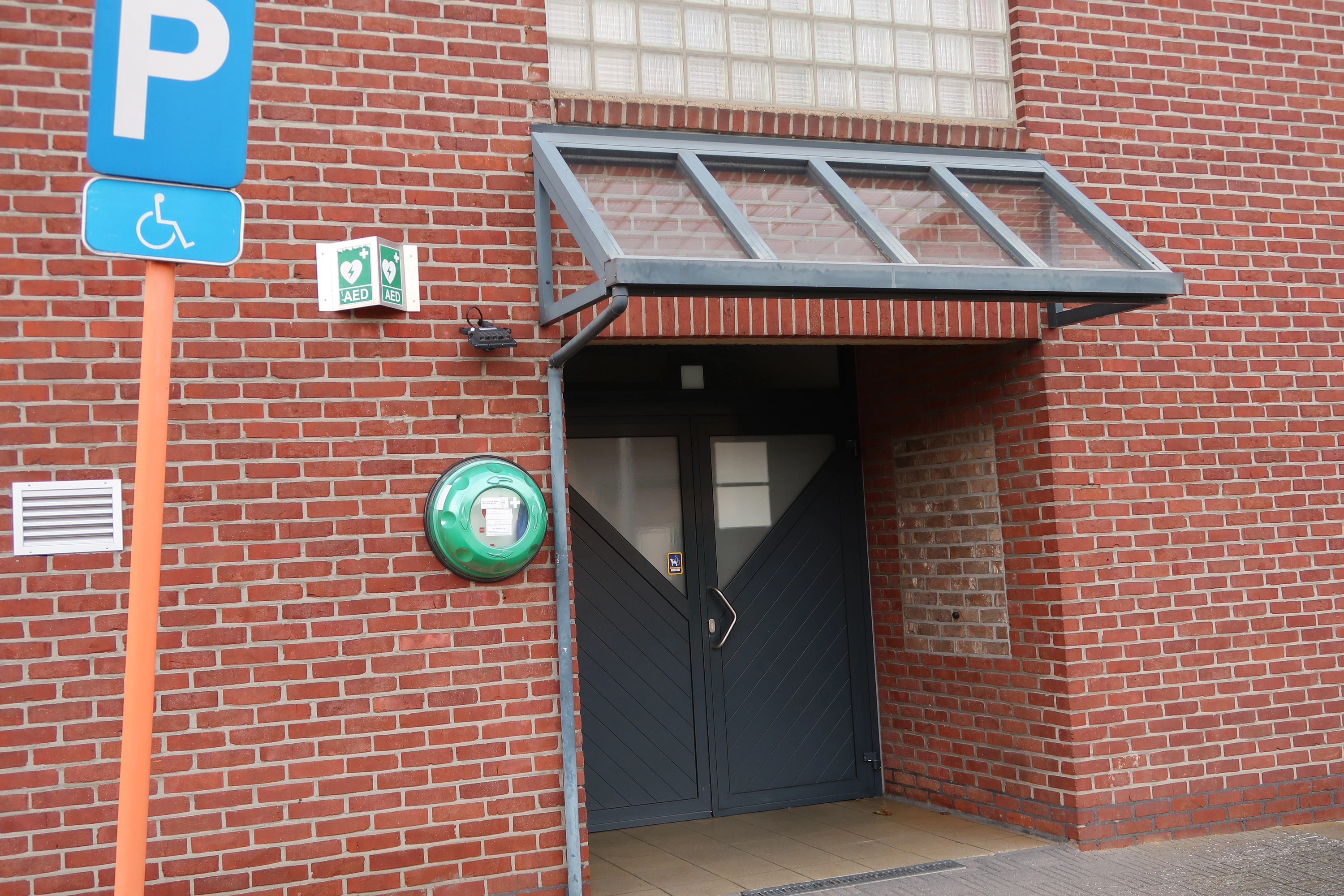 AED Tegen de voorgevel van zaal Elckerlyc,links van de ingang