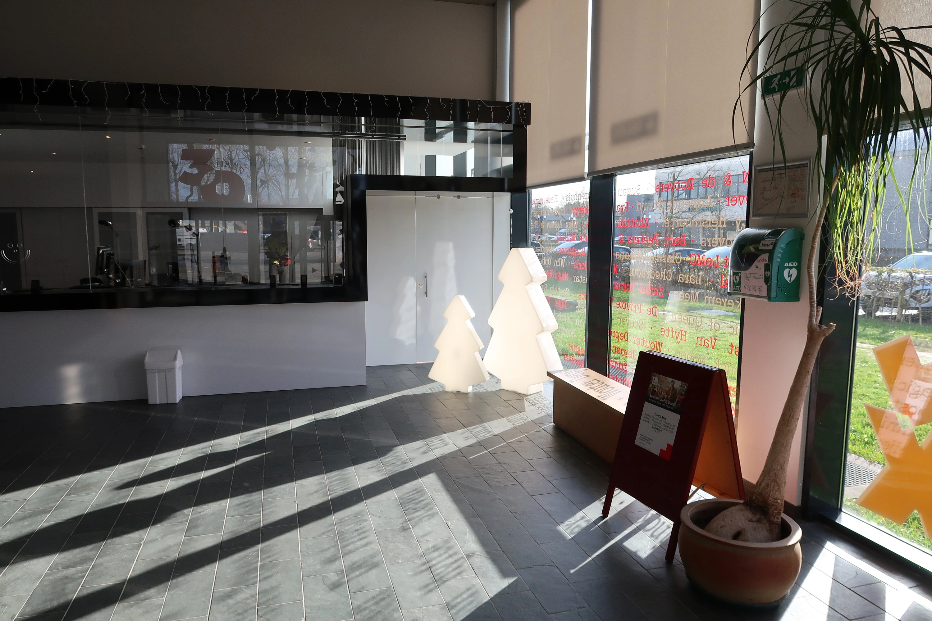AED Binnen in de foyer van de Velinx, rechts van het onthaal tussen de vensters