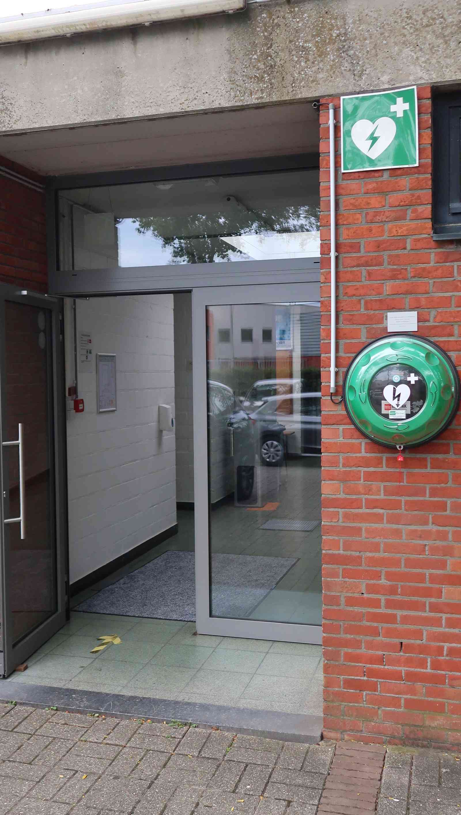 AED naast de ingang tegen de buitenmuur van Turnhal SAC